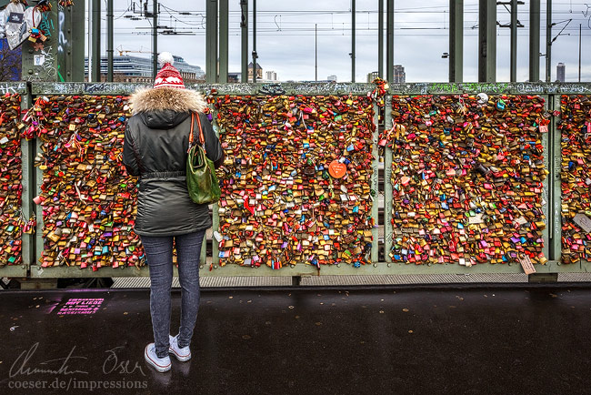 Ein Mädchen befestigt ein Liebesschloss an der Hohenzollernbrücke in Köln, Deutschland.