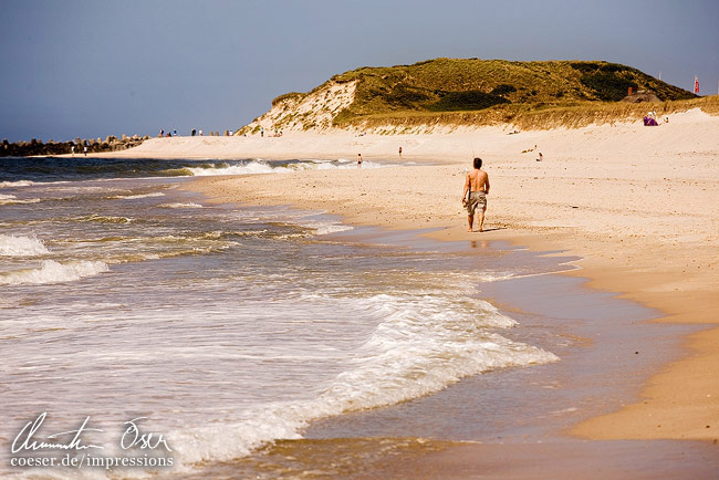 Ein Mann geht am Strand von Hörnum spazieren auf der Insel Sylt, Deutschland.