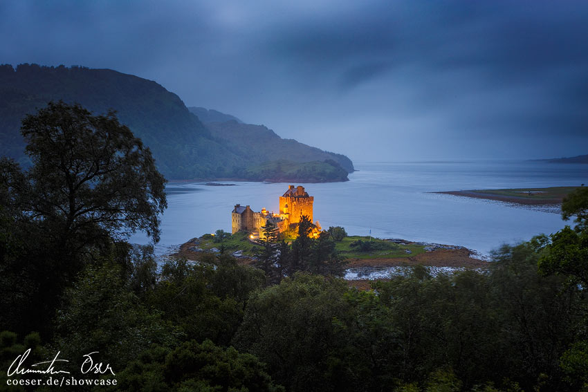 Beleuchtetes Eilean Donan Castle im Regen nach Sonnenuntergang in Dornie, Kyle of Lochalsh, Schottland.