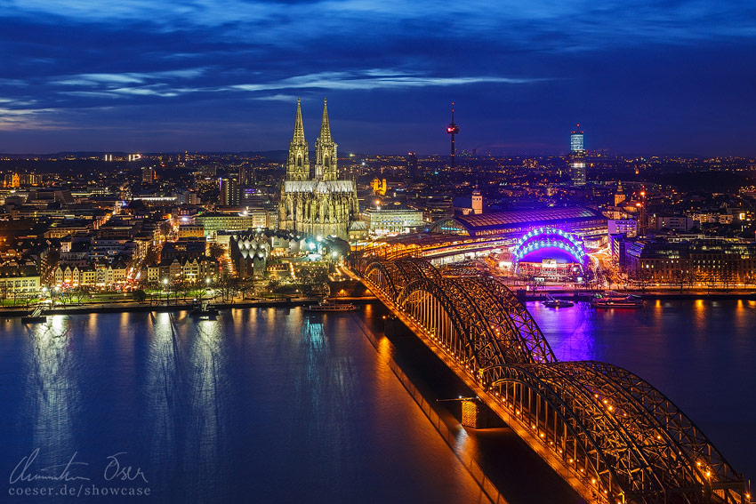 Stadtansicht mit dem Kölner Dom, der Hohenzollernbrücke und dem Hauptbahnhof während der blauen Stunde in Köln, Deutschland.