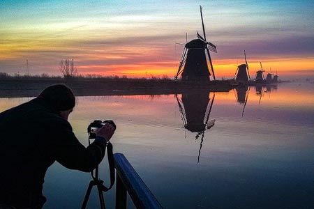 Fotograf Christian Öser während einer Aufnahme bei den Windmühlen von Kinderdijk, Niederlande
