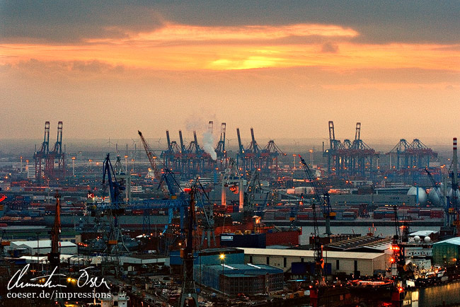 Der Sonnenuntergang beleuchtet Dutzende Kräne im Hafen von Hamburg, Deutschland.