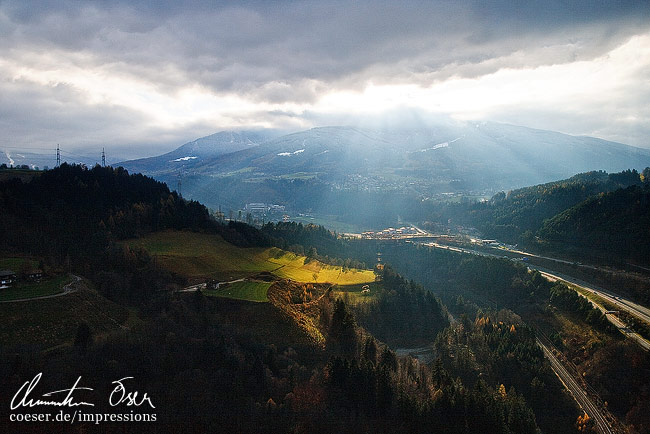 Sonnenstrahlen brechen durch Wolken, gesehen von der Bergisel-Aussichtsplattform in Innsbruck, Österreich.