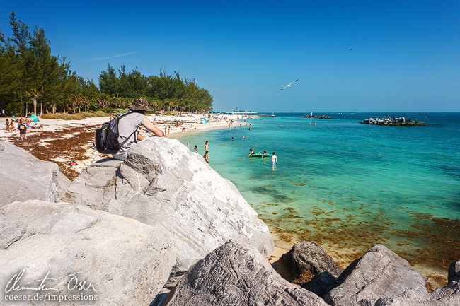Ein Mann sitzt auf einem Felsen am Zachary-Taylor-Strand in Key West, USA.