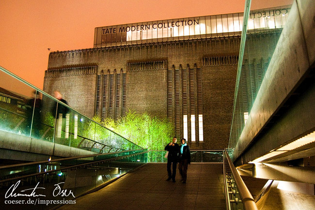 Die beleuchtete Tate Gallery of Modern Art, gesehen von der Millennium Bridge in London, Großbritannien.