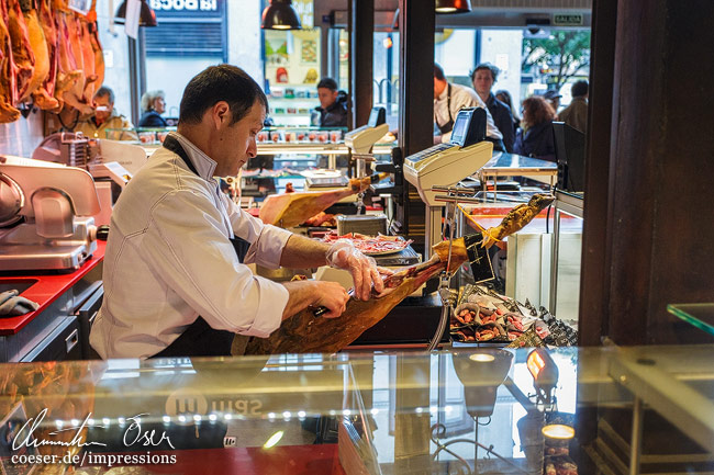 Ein Händler verkauft in der Markthalle Mercado San Miguel Schinken (Jamón) in Madrid, Spanien.