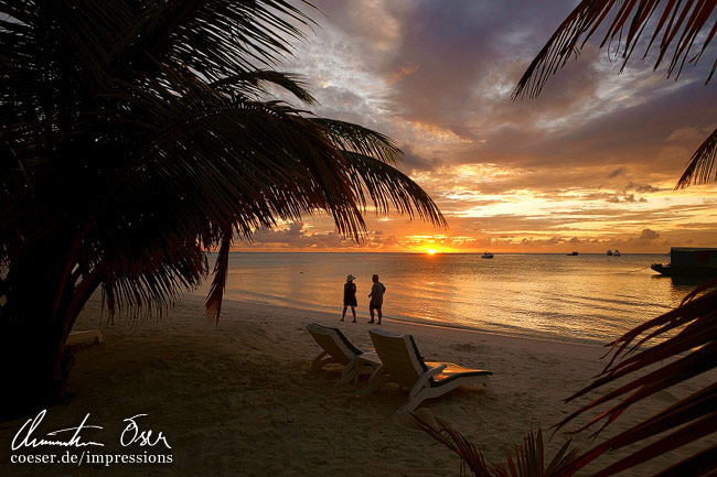 Menschen machen einen Spaziergang am Strand während eines Sonnenuntergangs auf der Meerufenfushi-Insel, Malediven.