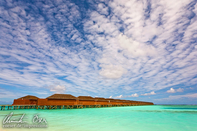 Jacuzzi-Wasserbungalows sind von türkisblauem Meer umgeben auf der Meerufenfushi-Insel, Malediven.