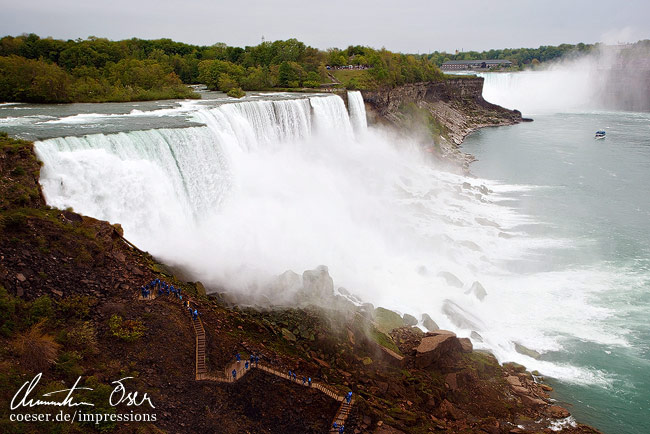 Menschen gehen einen Weg entlang der American Falls und Bridal Veil Falls (Niagarafälle) hinauf in Niagara City, USA.