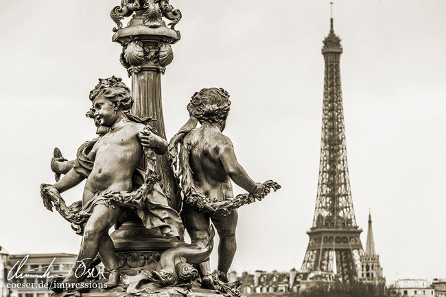 Engelsskulpturen auf der Brücke Pont Alexandre III und im Hintergrund der Eiffelturm in Paris, Frankreich.