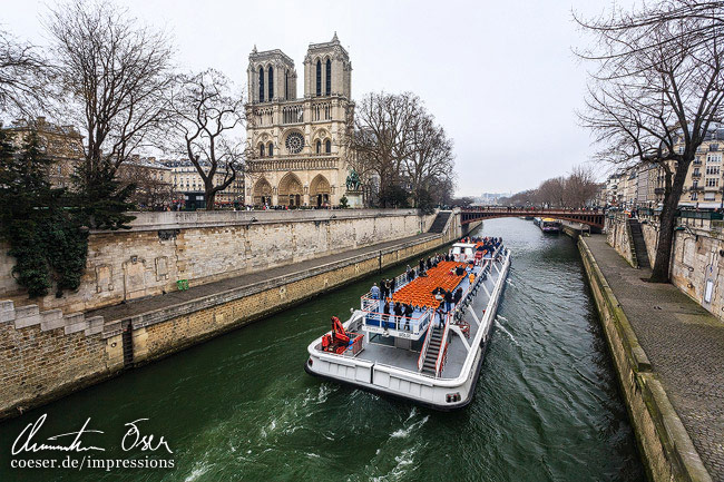 Ein Tour-Schiff auf der Seine fährt an der Kathedrale Notre-Dame de Paris vorbei in Paris, Frankreich.