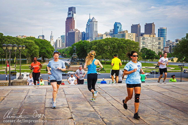 Läufer trainieren auf den Rocky Steps beim Museum of Art vor der Skyline von Philadelphia, USA.